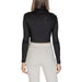 Woman wearing a black turtleneck crop top and light-colored sweatpants
