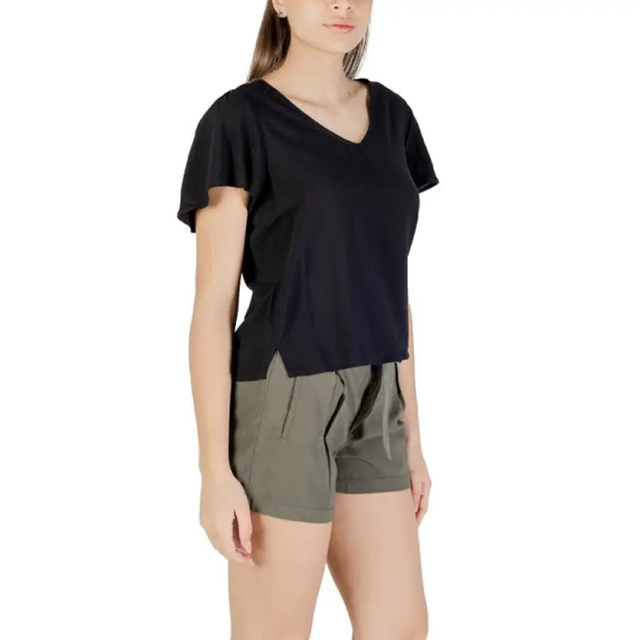 Woman wearing black V-neck flutter sleeve top and green shorts for a stylish casual look