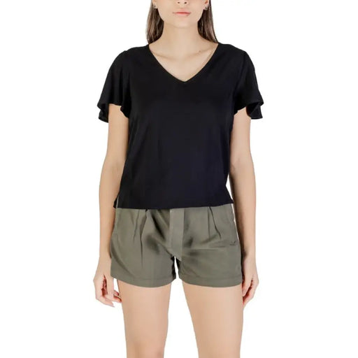 Woman wearing black V-neck flutter-sleeve top and green shorts in product display