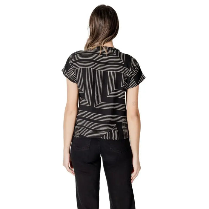 Woman wearing a black and white patterned blouse with black pants showcasing elegant style