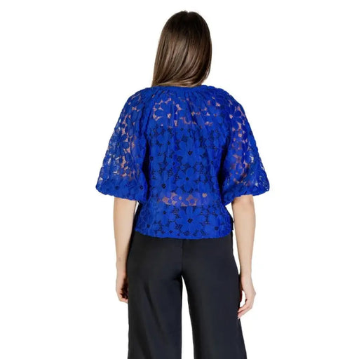 Elegant woman’s blue floral lace blouse paired with black pants for stylish occasions