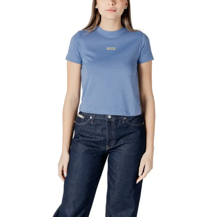 Woman wearing blue T shirt and dark jeans, showcasing Womens Beige T Shirt and White Denim Shorts