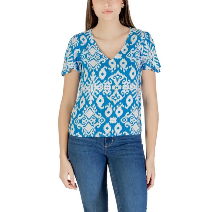 Woman wearing blue and white patterned blouse paired with black V neck flutter sleeve top and green shorts