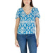 Woman wearing blue and white patterned blouse paired with black V neck flutter sleeve top and green shorts