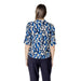 Woman’s blue and white patterned blouse paired with dark pants in product image
