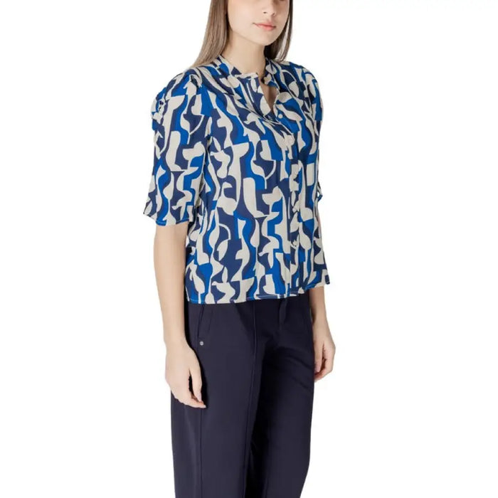 Woman wearing a blue and white patterned blouse with dark pants