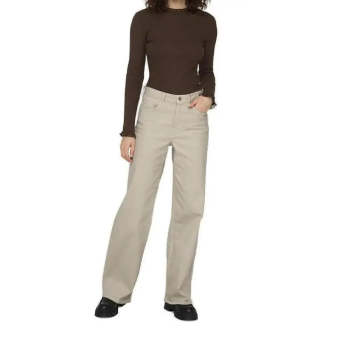 Woman wearing a brown long-sleeved shirt with beige pants and jeans