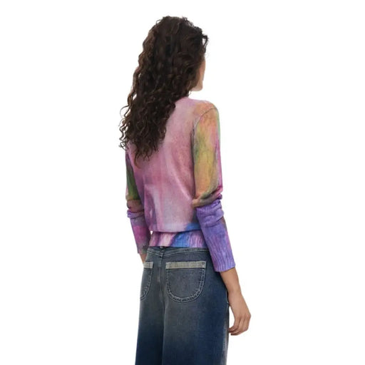 Woman wearing a colorful long-sleeved tie-dye top and denim skirt for the Sheer Tie Dye collection