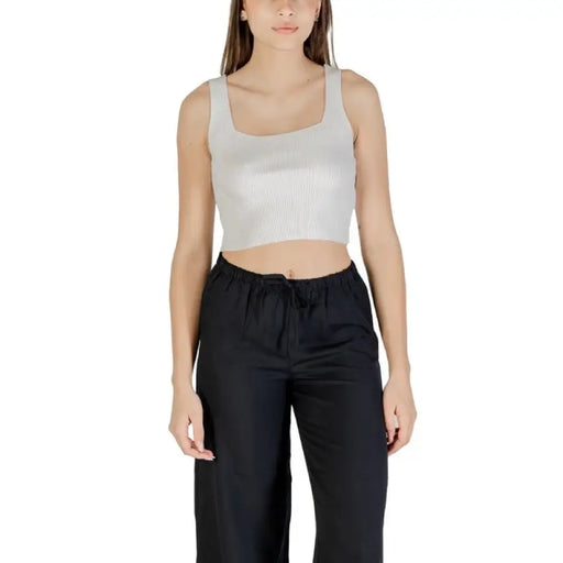 Woman wearing cropped tank top and black pants standing confidently