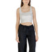 Woman wearing cropped tank top and black pants standing confidently