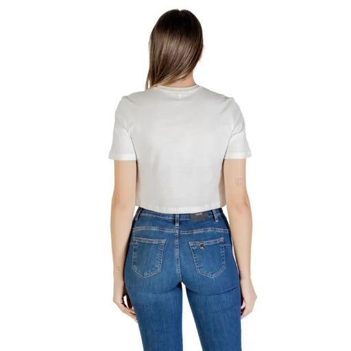 Woman wearing a white layered top and blue jeans for a casual fashion look