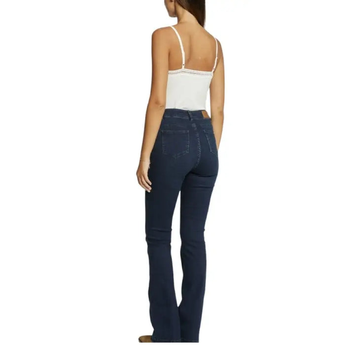 Woman wearing dark wash bootcut jeans paired with a white camisole top