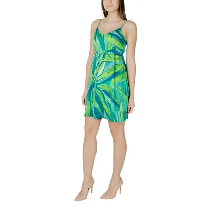 Woman wearing a green and blue patterned sundress showing intricate floral design