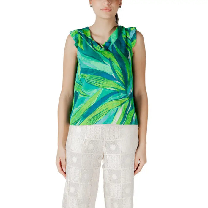 Woman wearing green leaf-patterned sleeveless top and white lace pants for floral print top