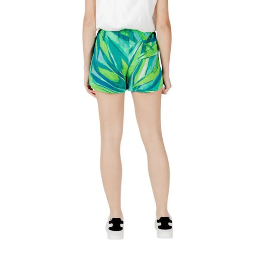 Woman wearing stylish green leaf patterned shorts in a fashion retail display