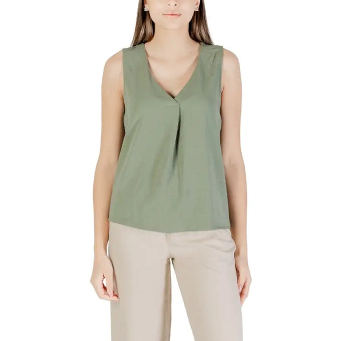 Woman wearing a green sleeveless top in front of a red sleeveless V neck blouse display