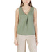 Woman wearing a green sleeveless top in front of a red sleeveless V neck blouse display