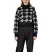 Woman wearing a houndstooth turtleneck sweater and black pants, suitable for stylish winter wear