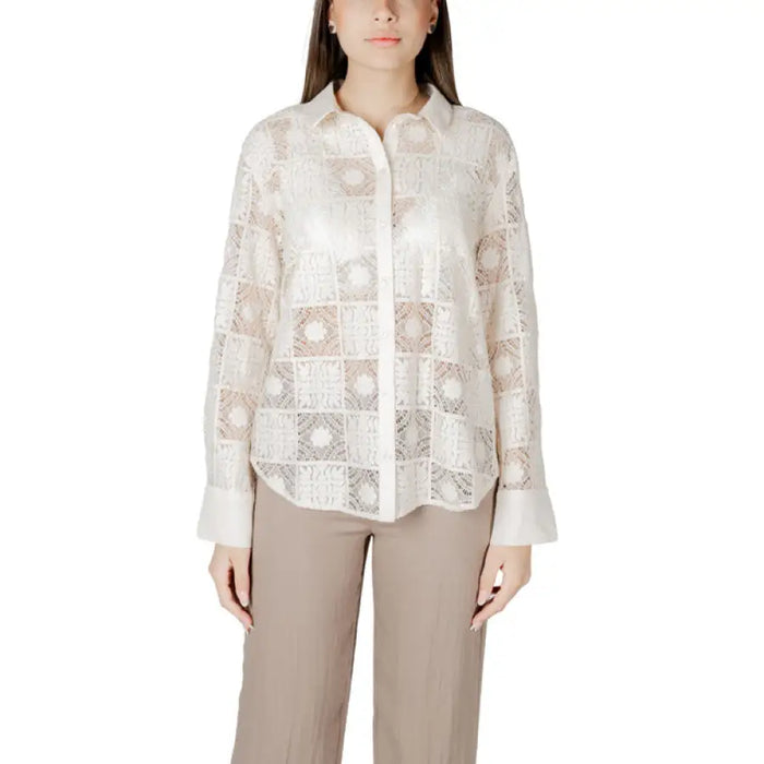 Woman wearing a black lace button-down shirt and tan pants exhibiting elegant fashion style