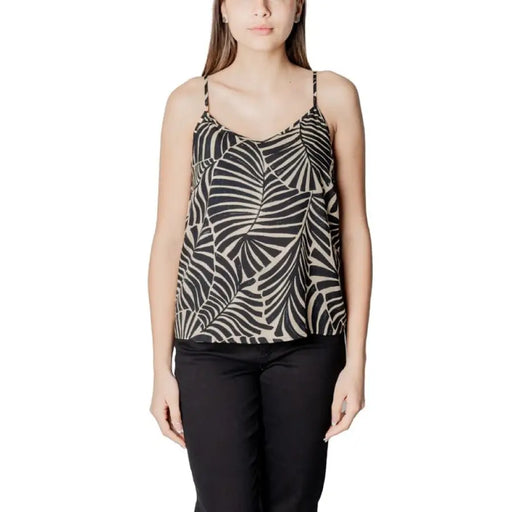 Woman wearing leaf-patterned camisole and black pants showcasing stylish comfort
