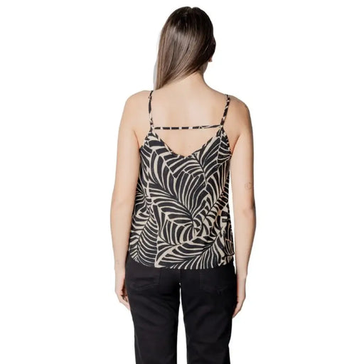 Woman wearing leaf-patterned camisole and black pants showcasing elegant casual style