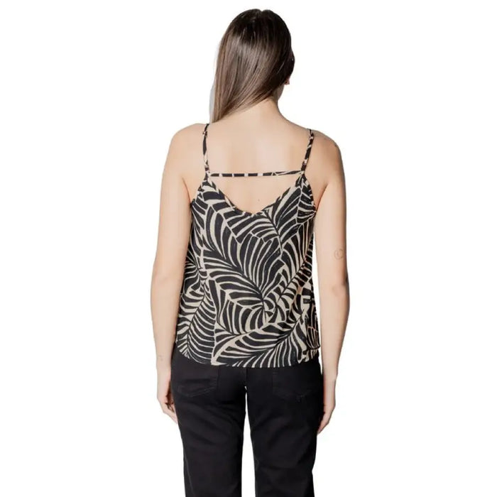 Woman wearing leaf-patterned camisole and black pants showcasing elegant casual style