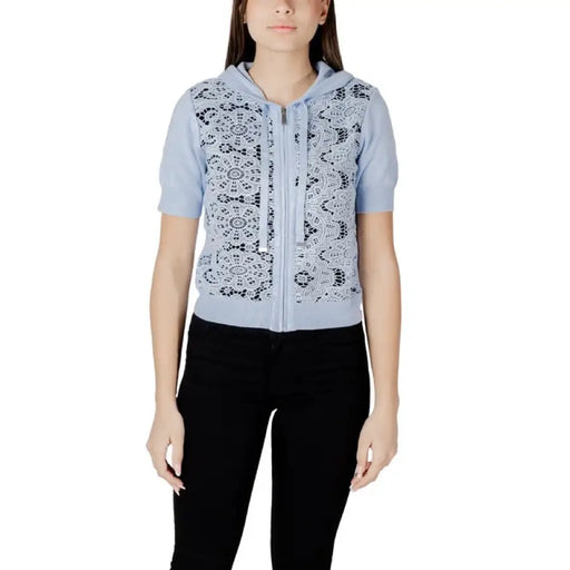 Woman wearing a light blue lace-front hooded cardigan with black pants