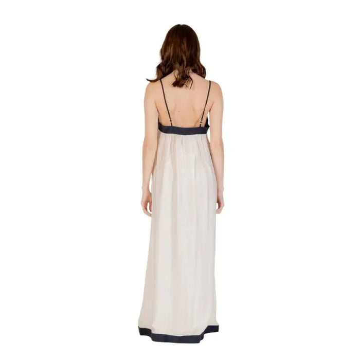 Elegant woman wearing a sleeveless floor-length light-colored dress with dark trim