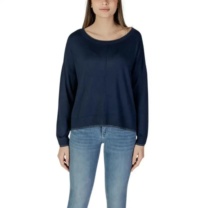 Woman wearing a navy blue long-sleeved sweater and jeans, showcasing Liu Jo T-shirt