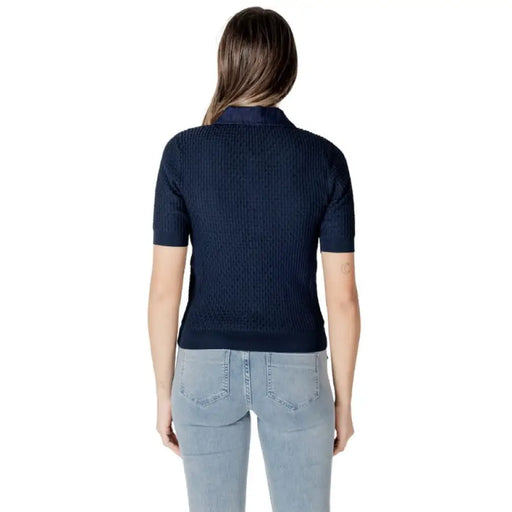 Woman wearing navy ribbed polo shirt and light blue jeans, stylish casual outfit
