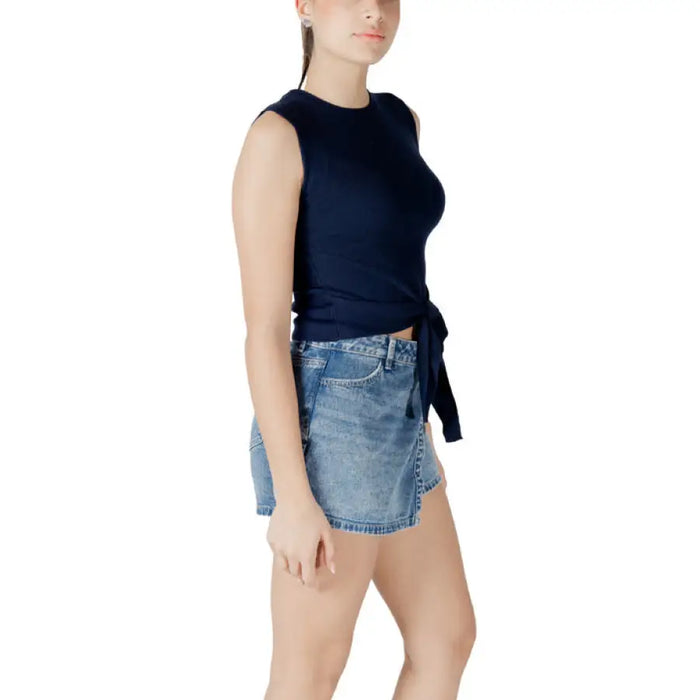 Woman wearing navy tie-front tank top and denim mini skirt for fashion style display