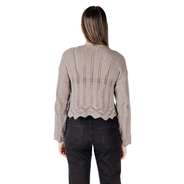 Woman wearing taupe long-sleeved open-knit sweater with scalloped hem