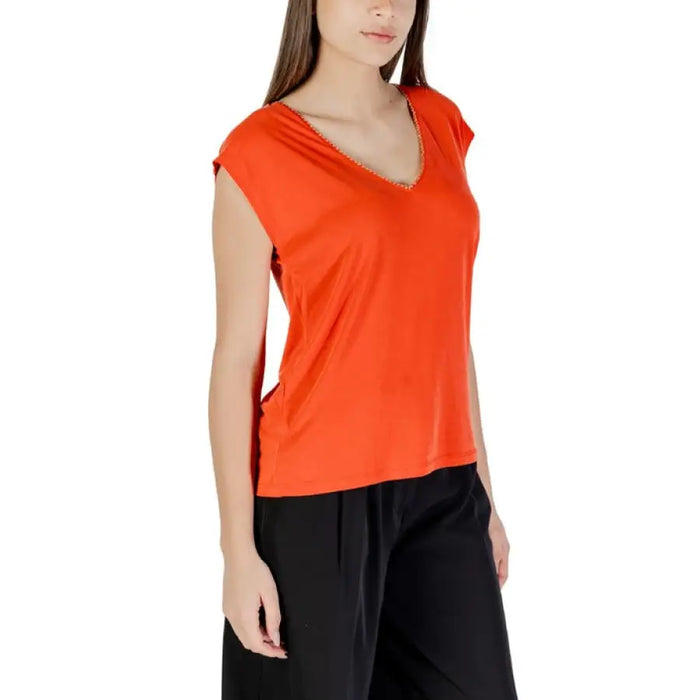 Woman wearing an orange V-neck top for women in a product display image