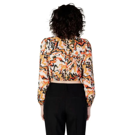 Woman in patterned crop top and black pants featuring Women’s Orange Blouse with Buttons