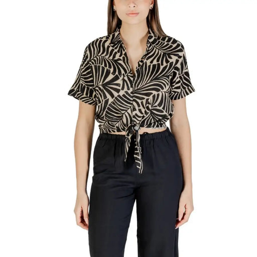 Woman wearing patterned tie-front shirt and dark pants, ideal for stylish office wear
