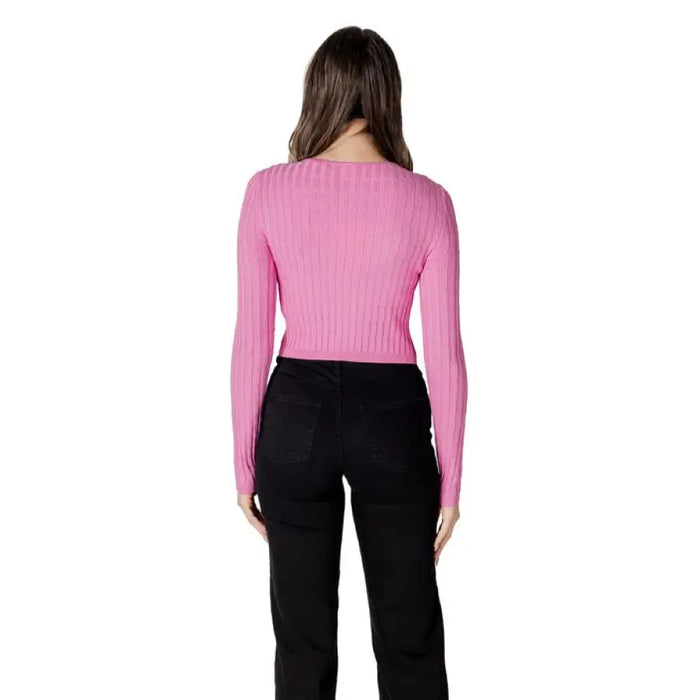 Woman wearing pink ribbed long-sleeve knit top with chest cutout and black pants