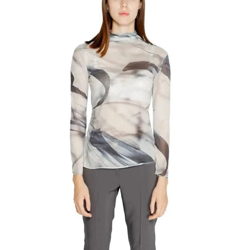 Woman wearing a sheer patterned long-sleeved top from Rinascimento Women’s Grey Printed Turtleneck Sweater