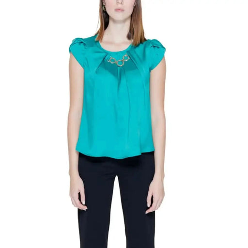 Woman wearing a teal Green Rinascimento blouse paired with black pants
