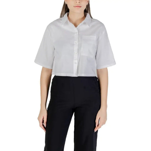 Woman wearing white cropped button-down shirt with black pants for a stylish look