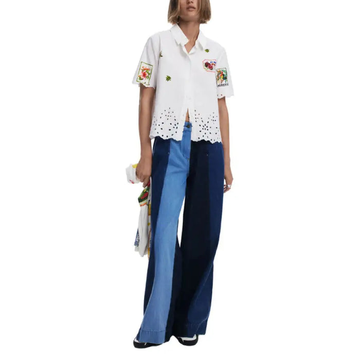 Woman wearing a white embroidered short-sleeved shirt and color-blocked jeans