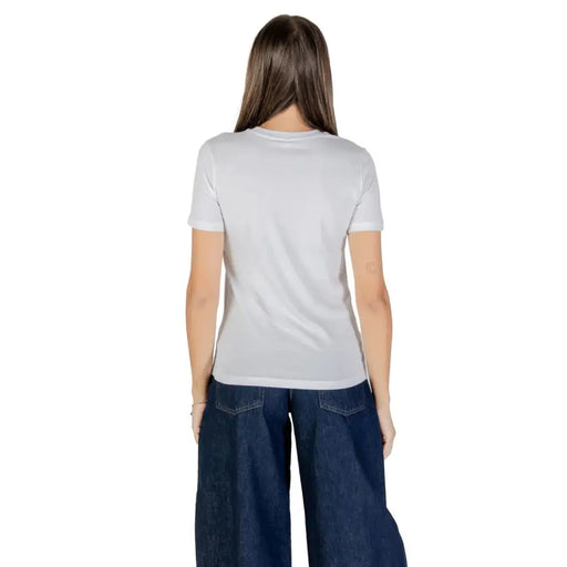 Woman wearing white 100% cotton short sleeve crew-neck T-shirt and wide-leg dark wash jeans