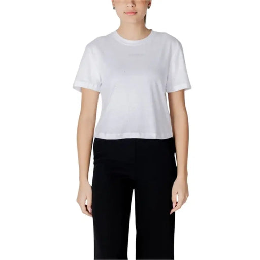 Woman wearing a white T shirt and black pants showcasing casual fashion style