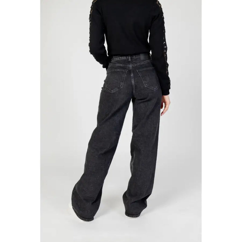 Jean noir à jambes larges pour femme, vu de dos, avec un délavage délavé et des poches arrière classiques.