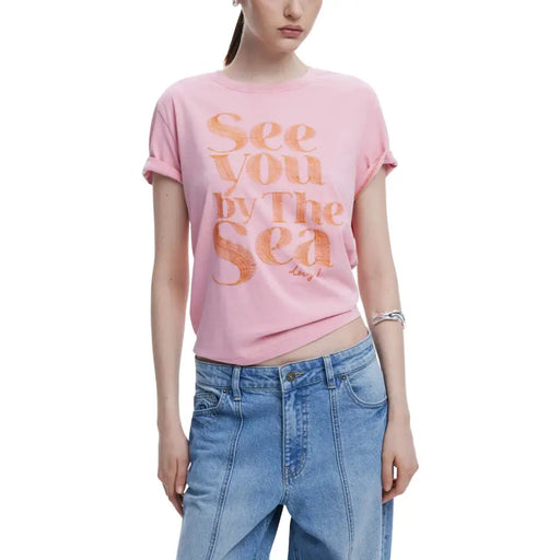 Women wearing pink graphic T-shirt with rolled sleeves and blue jeans from Desigual