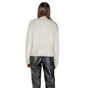 Cream-colored fuzzy knit sweater with long sleeves and round neck paired with black faux leather trousers
