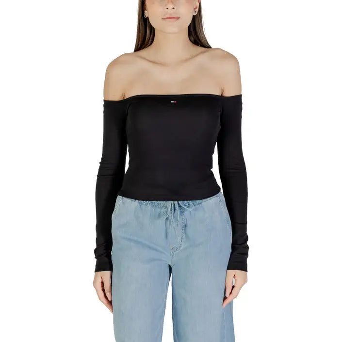 Woman wearing a black off-the-shoulder long-sleeve top with light blue pants