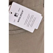 White woolrich brand tag with black text and logo attached to beige fabric of woolrich men green cotton shorts spring summer collection