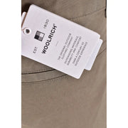 White woolrich brand tag with black text and logo attached to beige fabric of woolrich men green cotton shorts spring summer collection